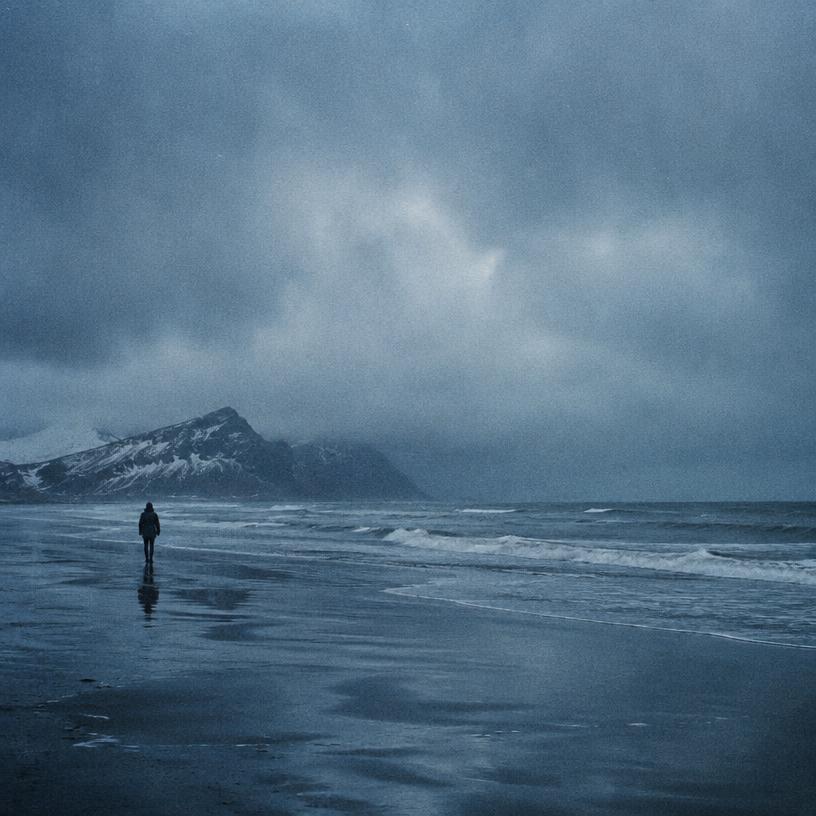 Playa bajo un cielo nublado, con una persona caminando